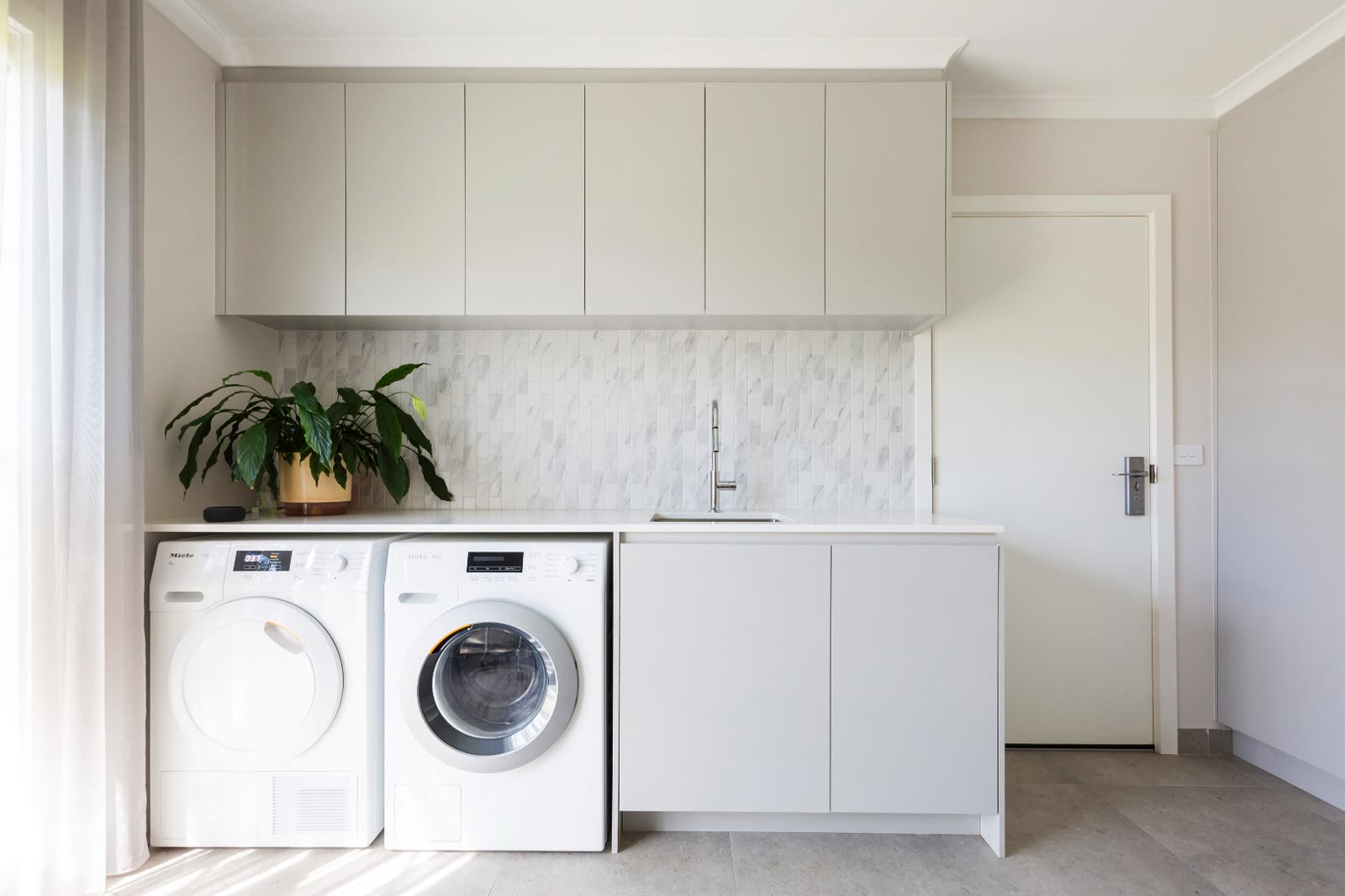 Weetangera laundry with marble splashback and integrated cabinetry